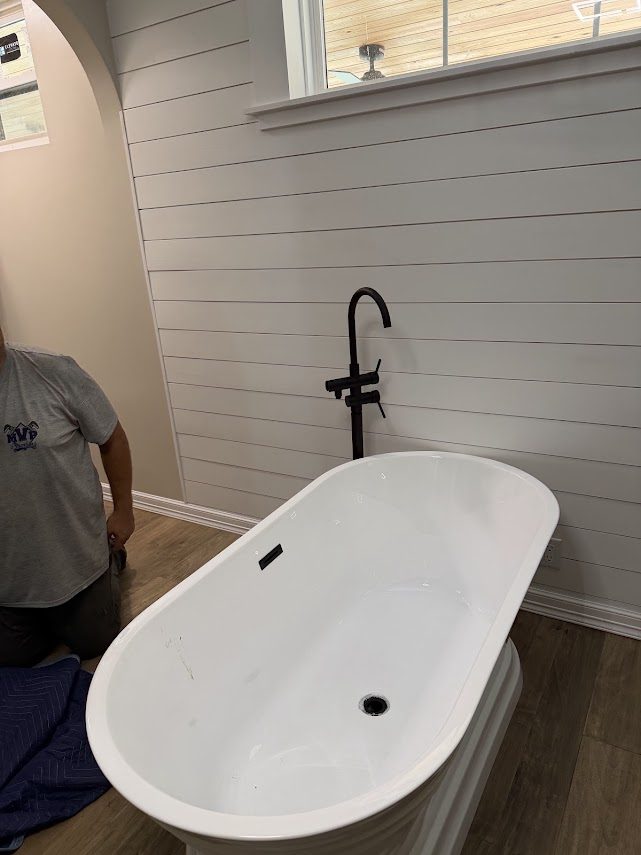 Freestanding tub on a floor-mounted filler, finished, in an Anahuac whole-house plumbing remodel