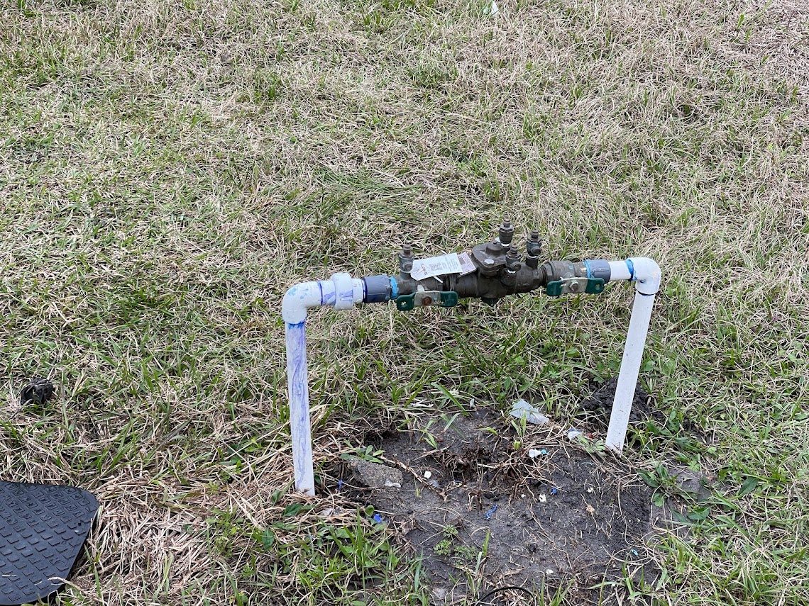 Small double-check backflow assembly on PVC risers in a residential yard