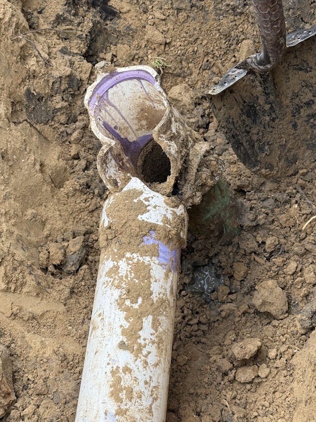 Crushed and split sewer pipe at the joint with dirt packed inside
