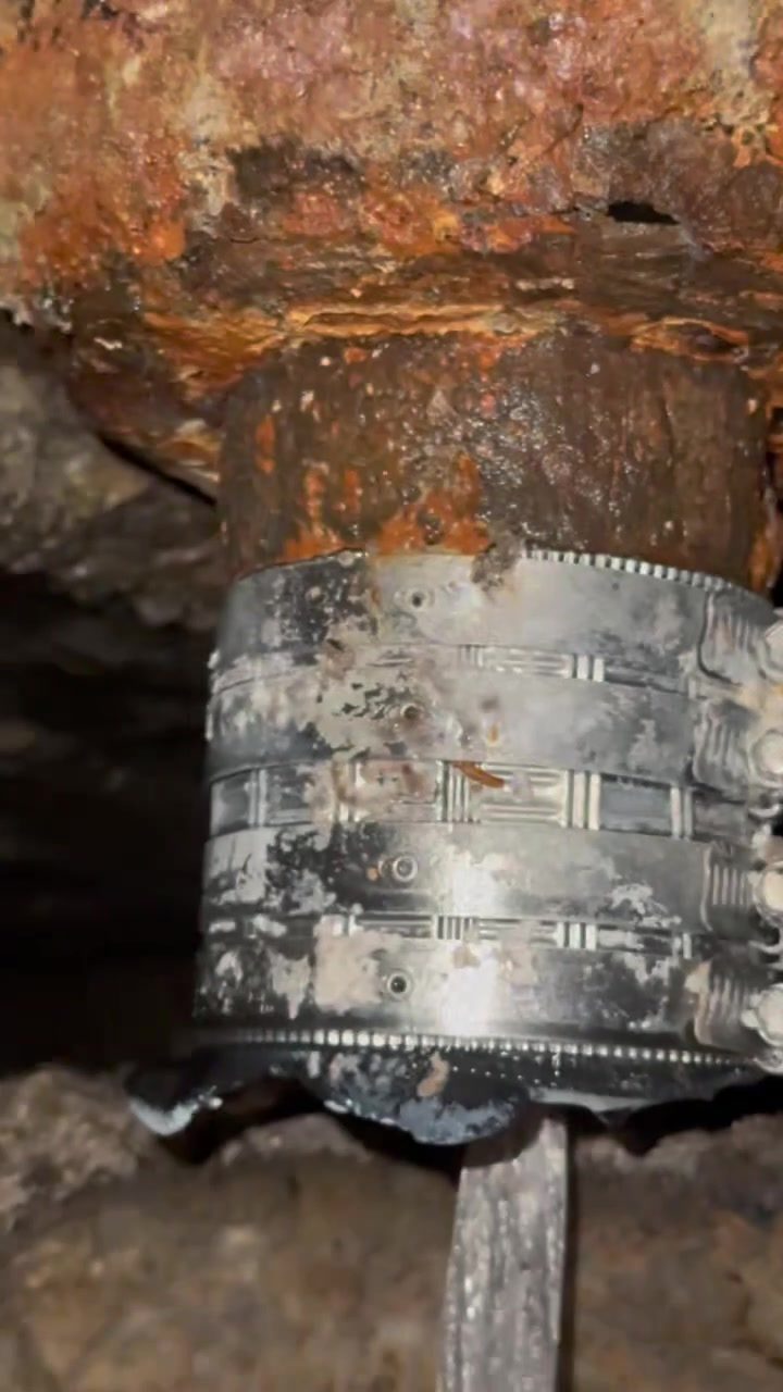 New shielded no-hub coupling banded onto a rusted cast iron drain pipe