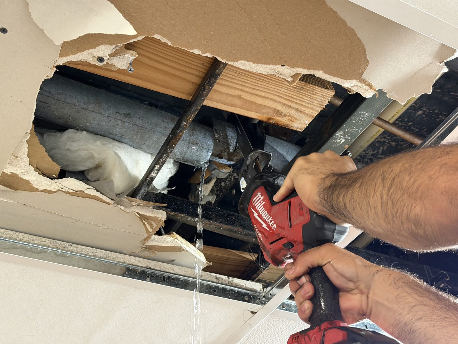 Commercial ceiling opened to expose an actively leaking pipe