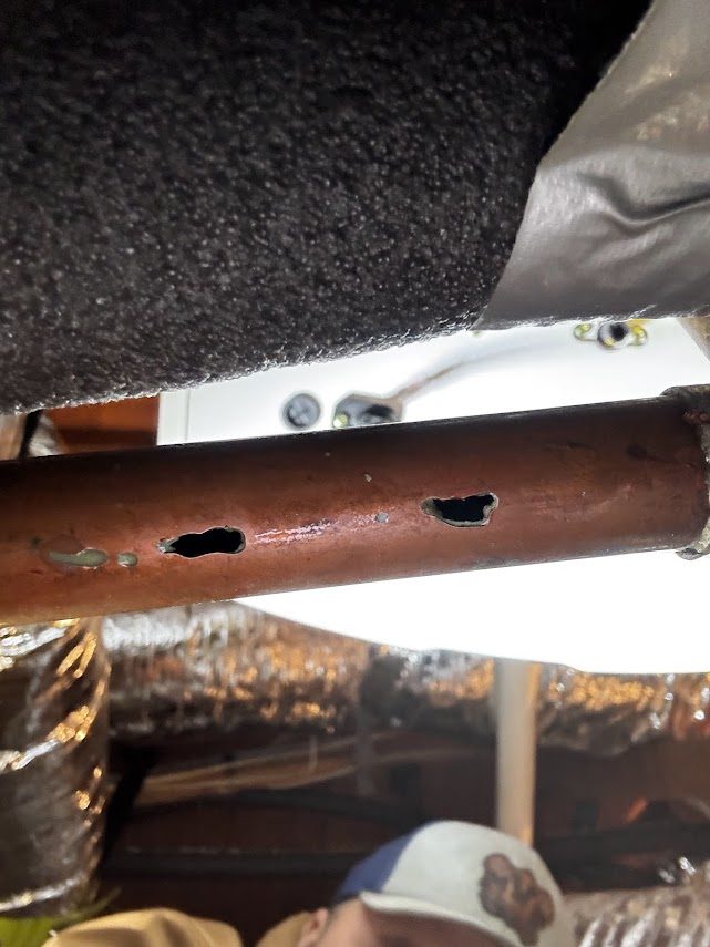 Corroded copper water pipe with pinhole leaks worn clean through the wall of the pipe