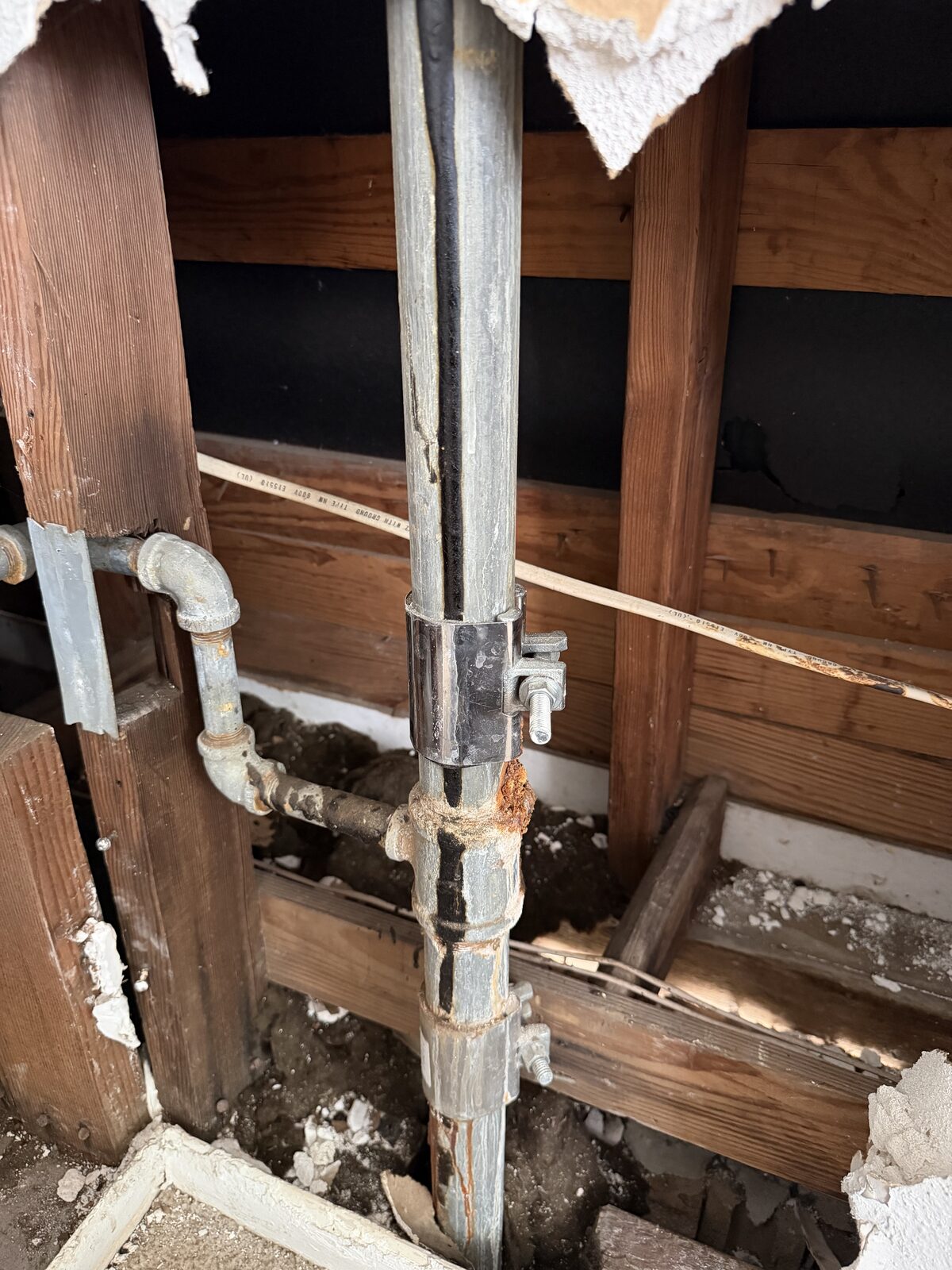 Original galvanized riser rusted through at a joint inside an opened apartment wall in Baytown, TX