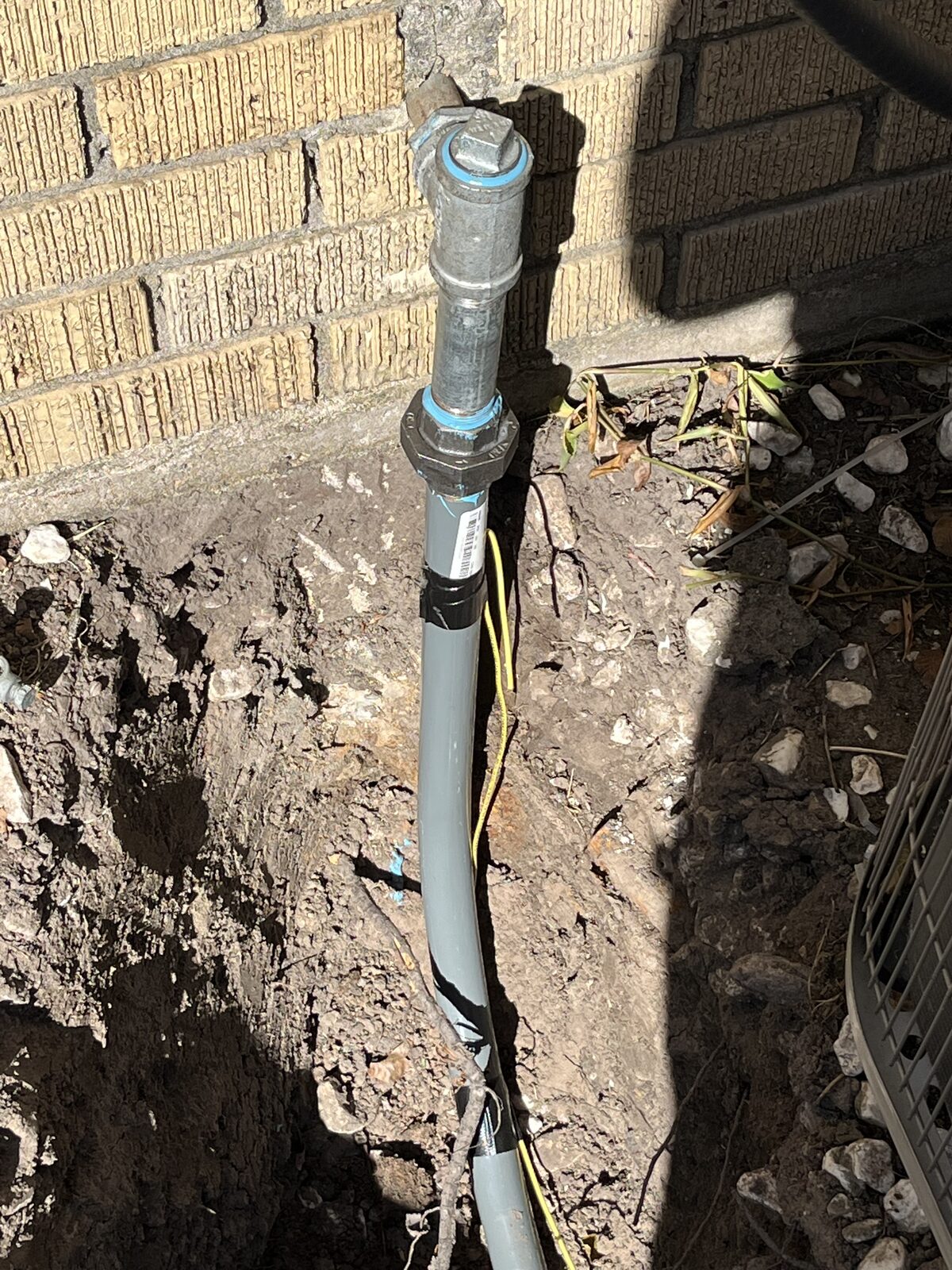Gas riser at a brick wall connected to buried polyethylene yard line in a trench