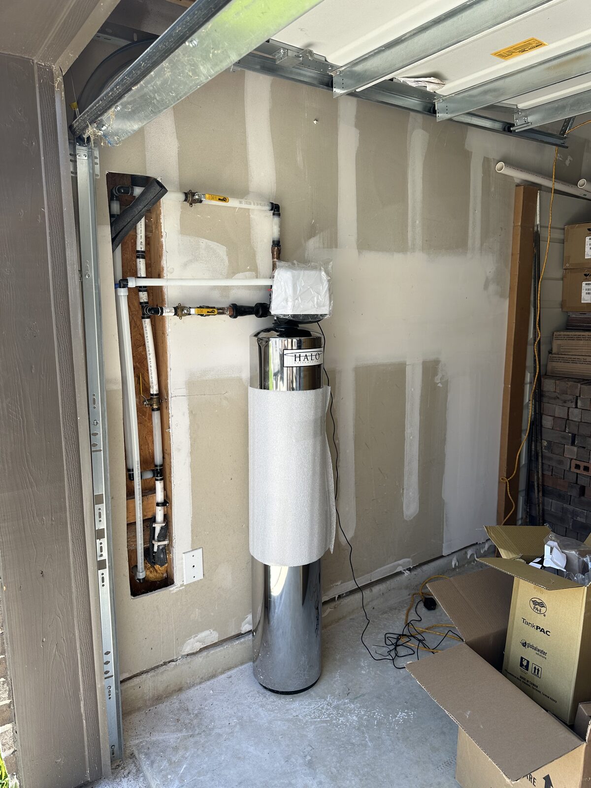 HALO whole-house water conditioner installed in a garage with a PEX manifold and isolation valves