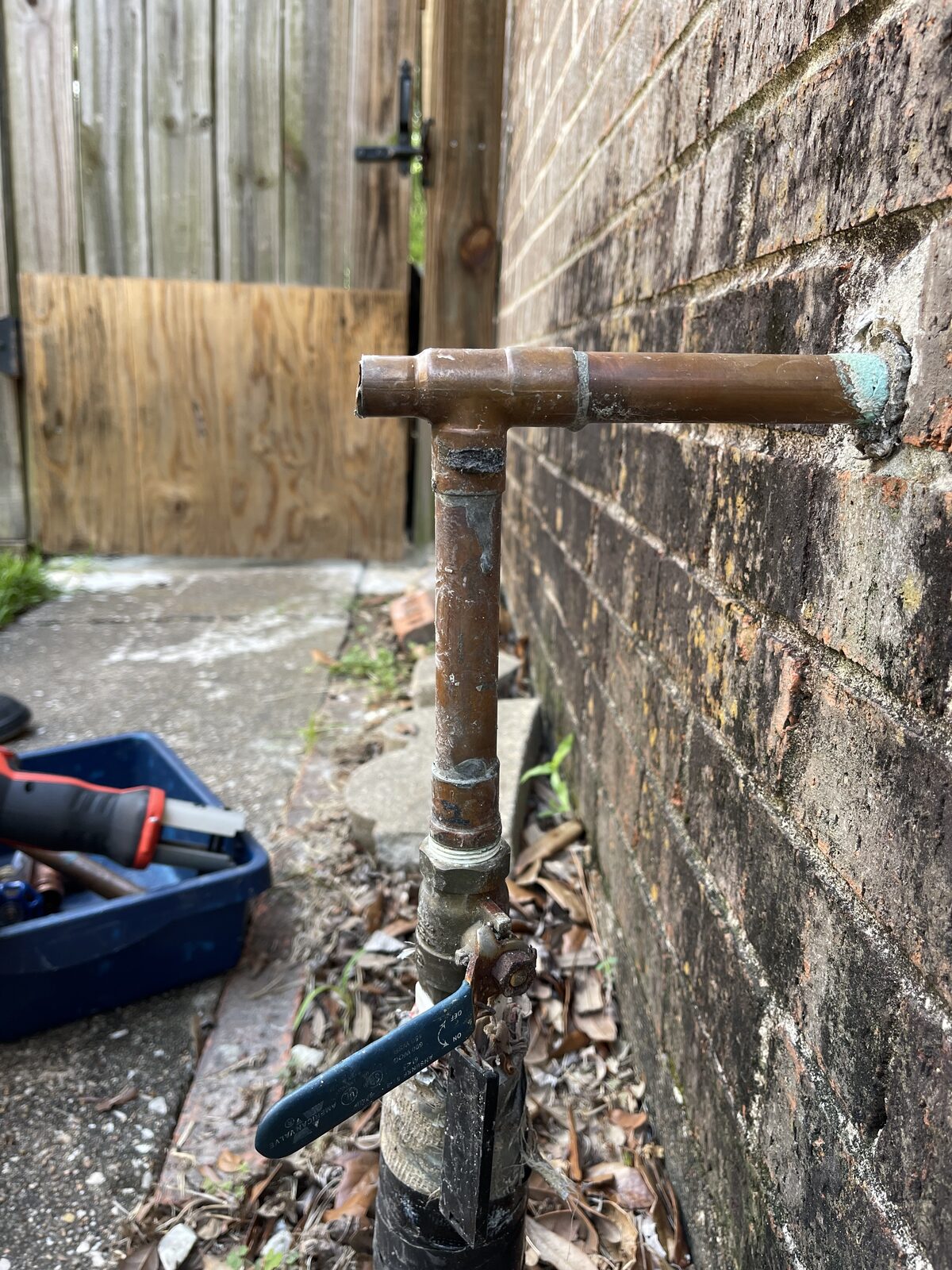 Old copper hose bib at a wall before replacement