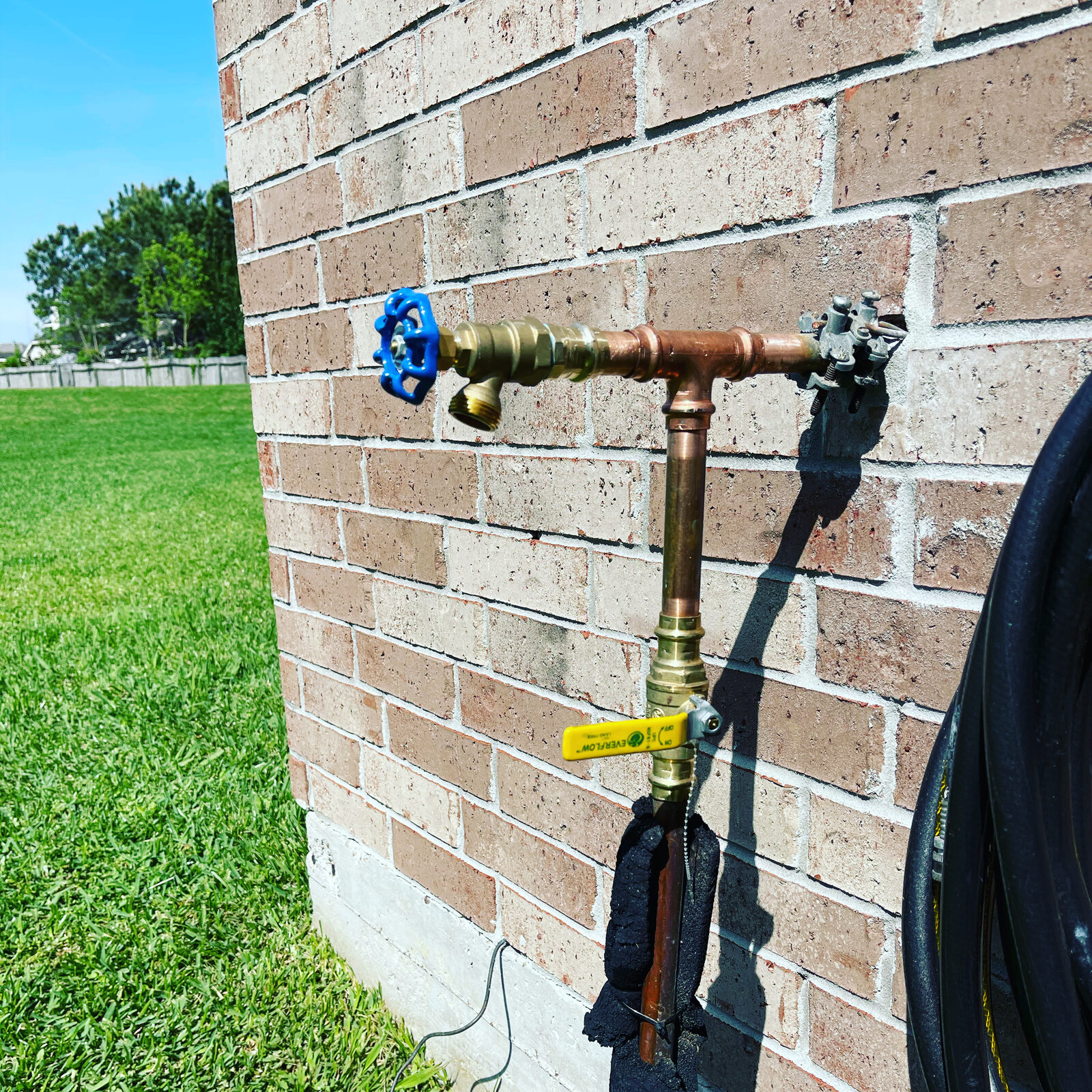 Hose bib with its own shutoff valve, insulated, on a brick wall