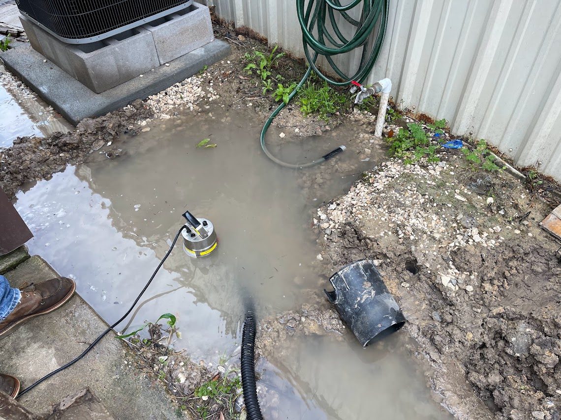Submersible pump clearing standing water from an excavation to expose a leak