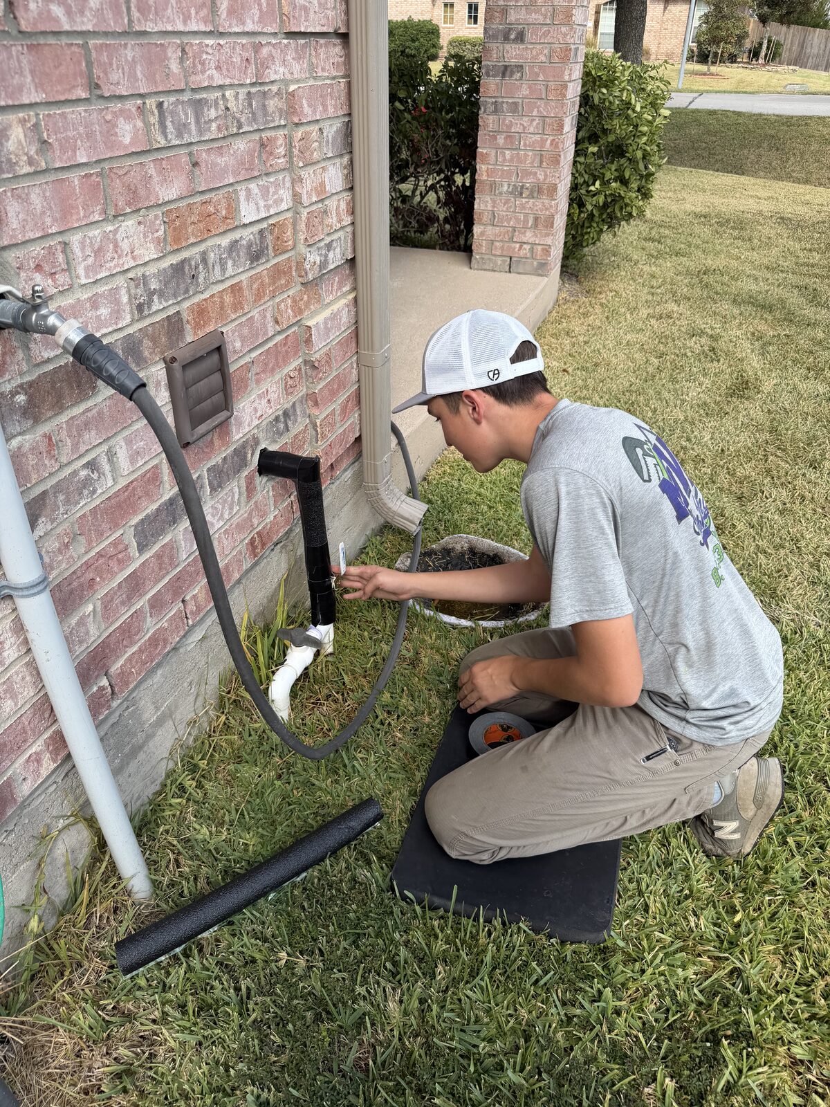 MVP Plumbing technician working on a water line repair at the brick, kneeling on a mat