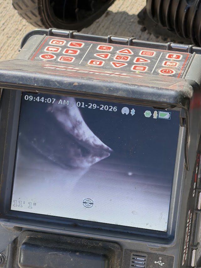 Sewer camera monitor showing a live view inside a pipe, with footage counter and date on screen
