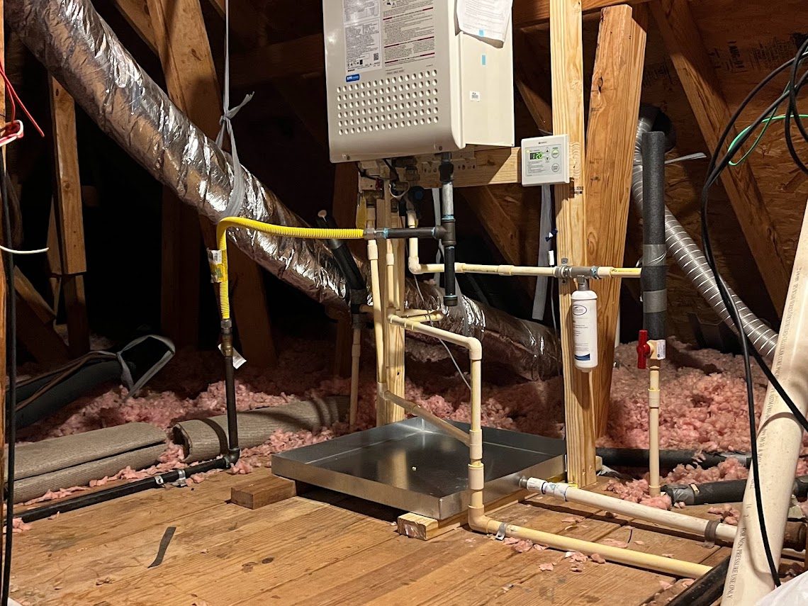 Finished tankless water heater installation in an attic with pan, gas flex, filter and controller