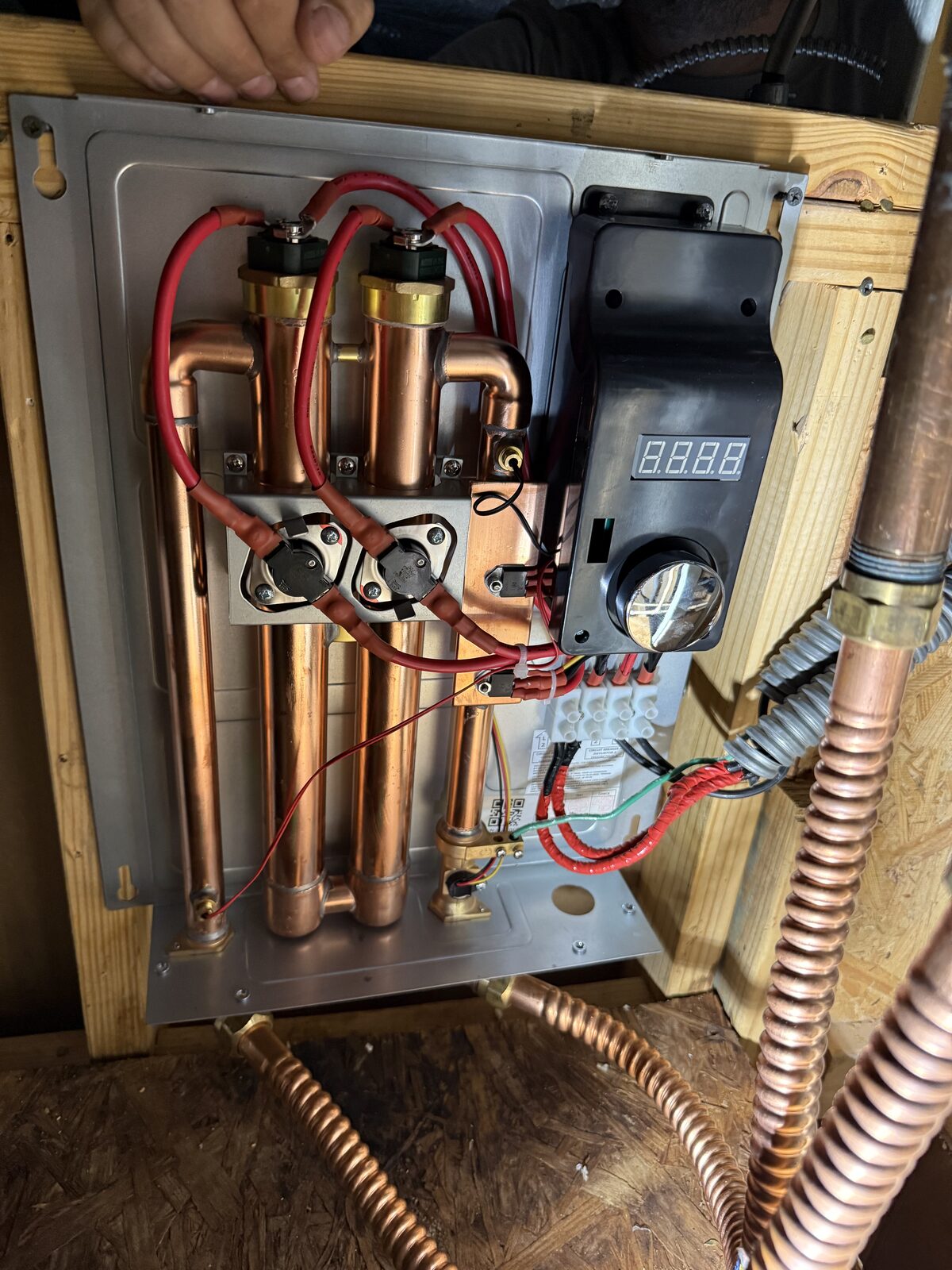 Inside an electric tankless water heater showing copper heating elements and controls