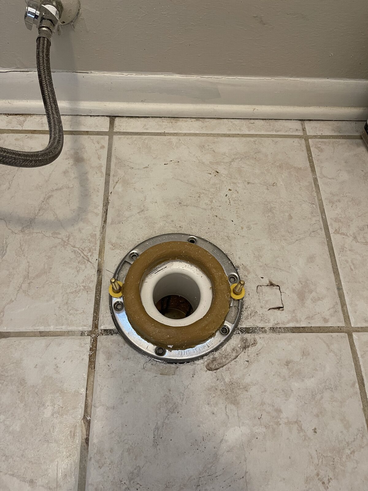 New stainless steel toilet flange set into the slab with a wax ring fitted