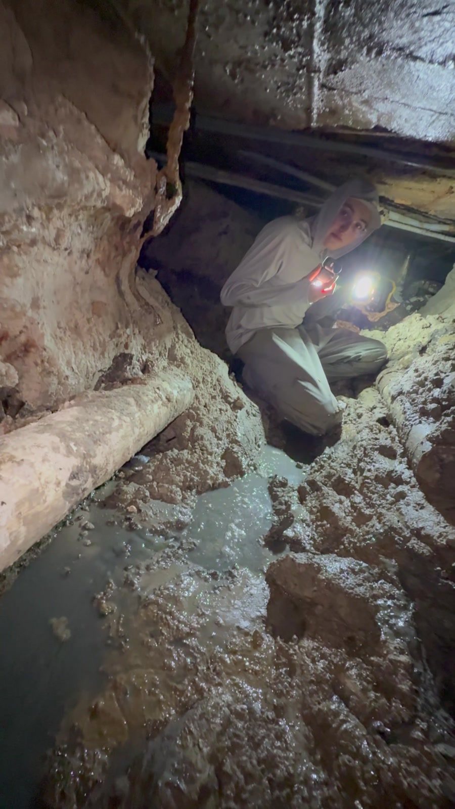 MVP Plumbing technician working by headlamp inside a tunnel dug under a house slab