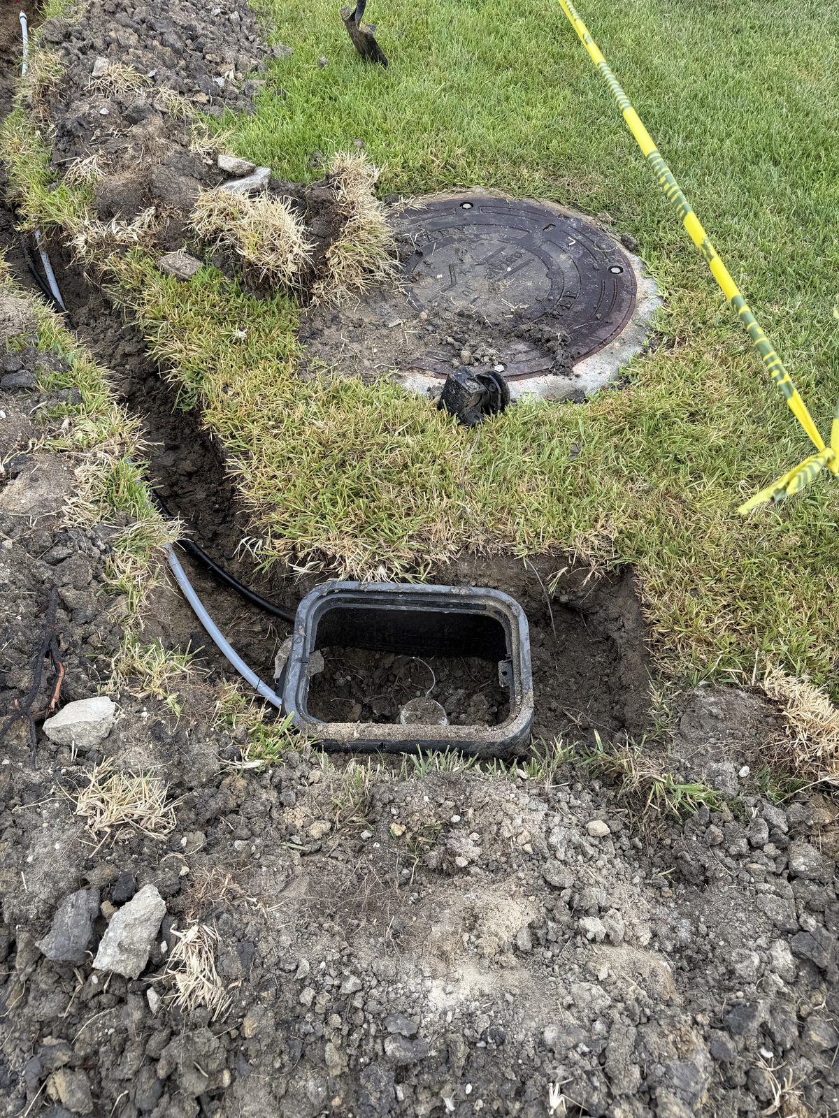 Water meter box lifted out of an open trench during a meter relocation in Mont Belvieu, TX, with the service line exposed